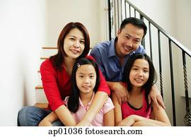 Family of four sitting on stairs, looking at camera, family portrait Family of four sitting on stairs, looking at camera, family portrait