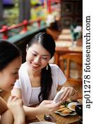 Frauen sitzen im Café und schauen sich das Handy an