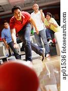 Man bowling, friends in the background, cheering Man bowling, friends in the background, cheering