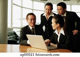 Executives in office, having a meeting, laptop open in front of them Executives in office, having a meeting, laptop open in front of them