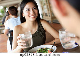 Couple having a meal in restaurant, holding glasses of water Couple having a meal in restaurant, holding glasses of water