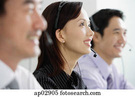 Executives in a row, wearing headsets, looking away Executives in a row, wearing headsets, looking away
