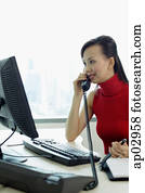Female executive sitting at office desk, using telephone Female executive sitting at office desk, using telephone