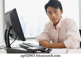 Male executive sitting at office desk, looking at camera Male executive sitting at office desk, looking at camera