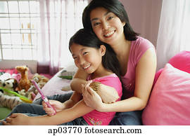 Mother hugging daughter, both looking at camera Mother hugging daughter, both looking at camera