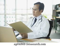 Doctor in office, looking at folder Doctor in office, looking at folder