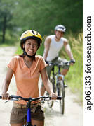 Couple cycling, woman in foreground, looking at camera Couple cycling, woman in foreground, looking at camera