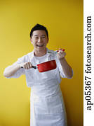 Man wearing apron and holding saucepan Man wearing apron and holding saucepan