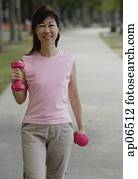 Mature woman using dumbbells in park Mature woman using dumbbells in park
