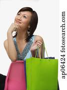 Young woman with shopping bags, looking away, hand on chin Young woman with shopping bags, looking away, hand on chin