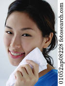 A young woman smiles at the camera as she washes her face