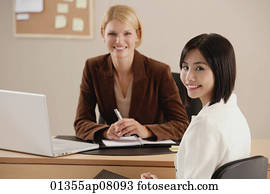 Two female colleagues smile at the camera together Stock ...