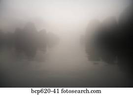 Rocks and water through mist at dawn