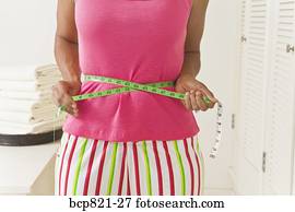 Woman measuring waist with measuring tape