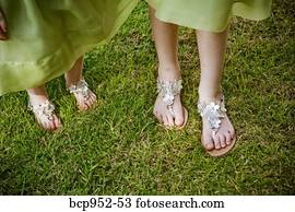 two pairs of feet in silver sandals