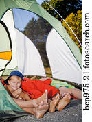 Young boy's face and pairs of feet poking out of tent