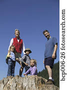 Family posing on a big tree stump.