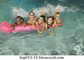 Group of kids in goggles on a pink float in a pool. Group of kids in goggles on a pink float in a pool.