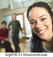 Woman in an office with two colleagues in the background.
