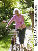 A senior woman walking her bicycle. A senior woman walking her bicycle.