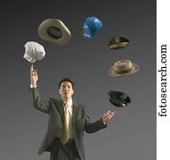 Young businessman juggling assorted hats