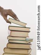 Human hand taking a book form a heap