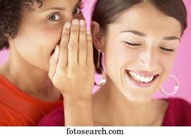 Portrait of a young women whispering into a woman's ear