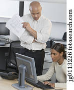 Businesswoman working on a computer a businessman standing beside her