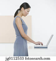 Side profile of a mid adult woman working on a laptop