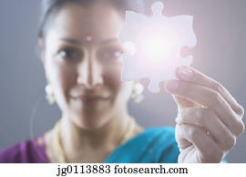 Close-up of a mid adult woman holding a jigsaw piece