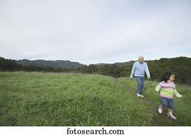 Grandfather running with his granddaughter in a field Grandfather running with his granddaughter in a field