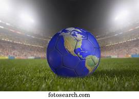 Soccer ball painted like a globe resting on grass in large stadium