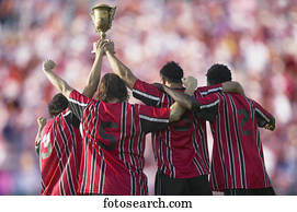 Soccer players triumphantly holding up trophy