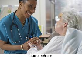 African female nurse holding patient's hand, Bethesda, Maryland, United States