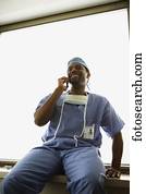 afrikanischer mann, chirurg, sitzen, in, fenster, nische, mit, mobilfunk