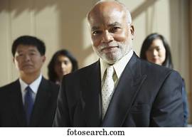 Middle-aged African businessman with co-workers in the background