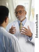 Middle-aged African doctor talking to co-worker