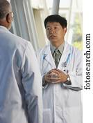 Middle-aged Asian doctor talking to co-worker