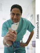 Middle-aged Indian male doctor holding out stethoscope, Bethesda, Maryland, United States