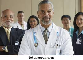 Middle-aged male African doctor with co-workers in the background