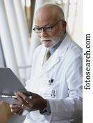 Senior male African doctor reading chart