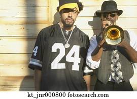 Young African man standing next to senior African man playing trumpet, Oakland, California, United States