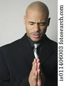 African American man in suit praying