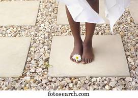 Close up of African American woman's bare feet with flower