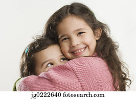 Studio shot of young Hispanic sisters hugging