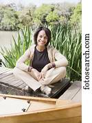 Middle-aged African woman sitting on dock smiling