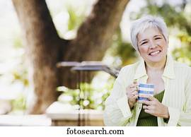 Middle-aged woman with coffee smiling outdoors