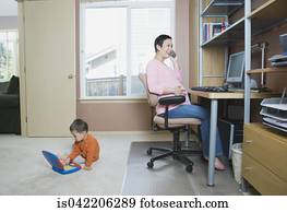 Pregnant woman working at home with young son