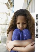 African girl leaning chin on knees outdoors