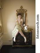 Woman in fancy dress with small dog on dresser